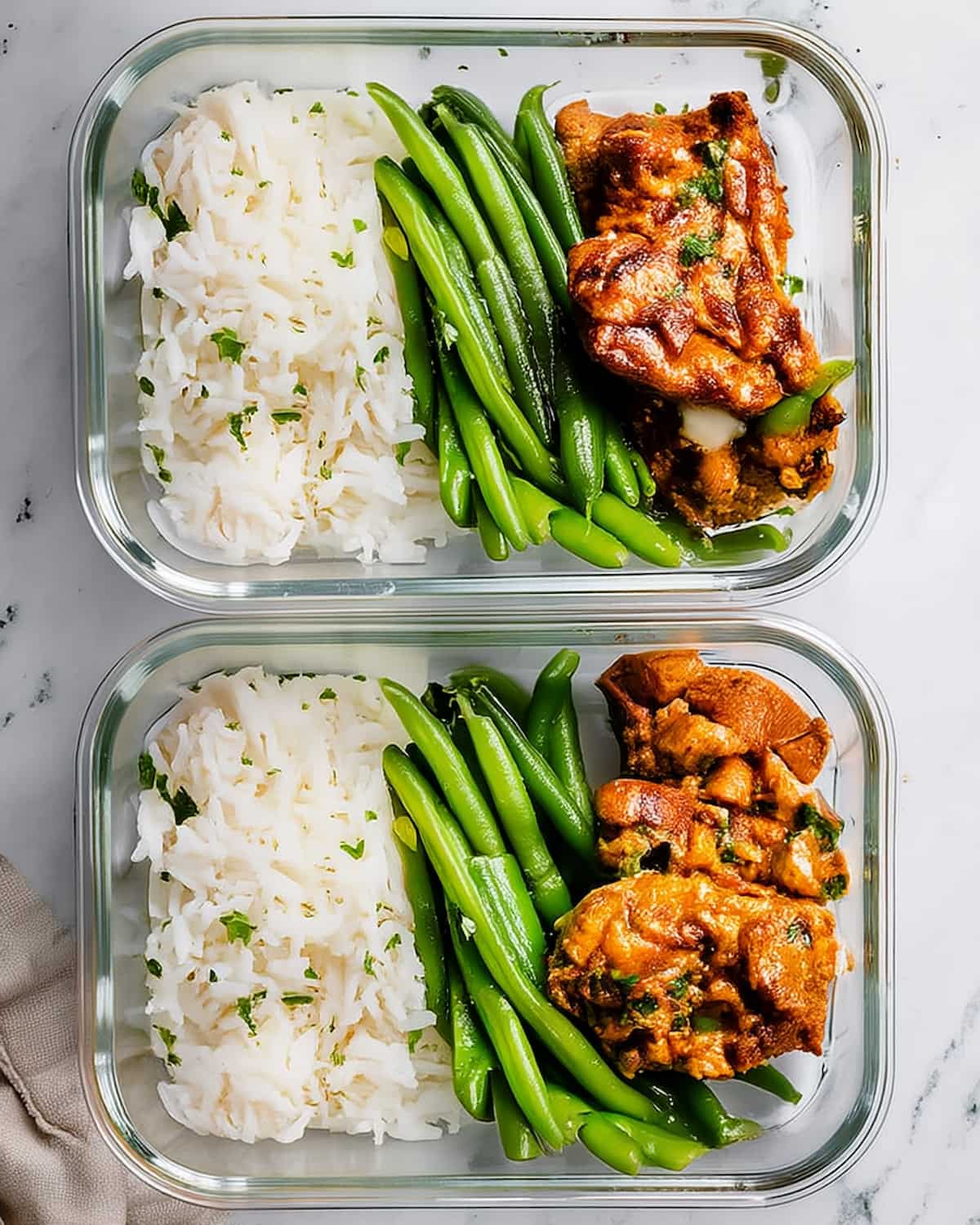 Chicken thighs meal prep containers with seasoned chicken, white rice with herbs, and crisp green beans.