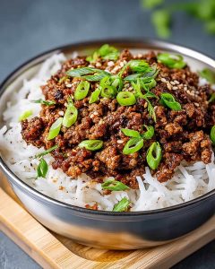 Ground beef and rice meal prep with seasoned beef over fluffy white rice, topped with fresh green onions.