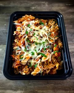 Lasagna meal prep container with fusilli pasta, tomato sauce, ground meat and melted cheese generously topped.
