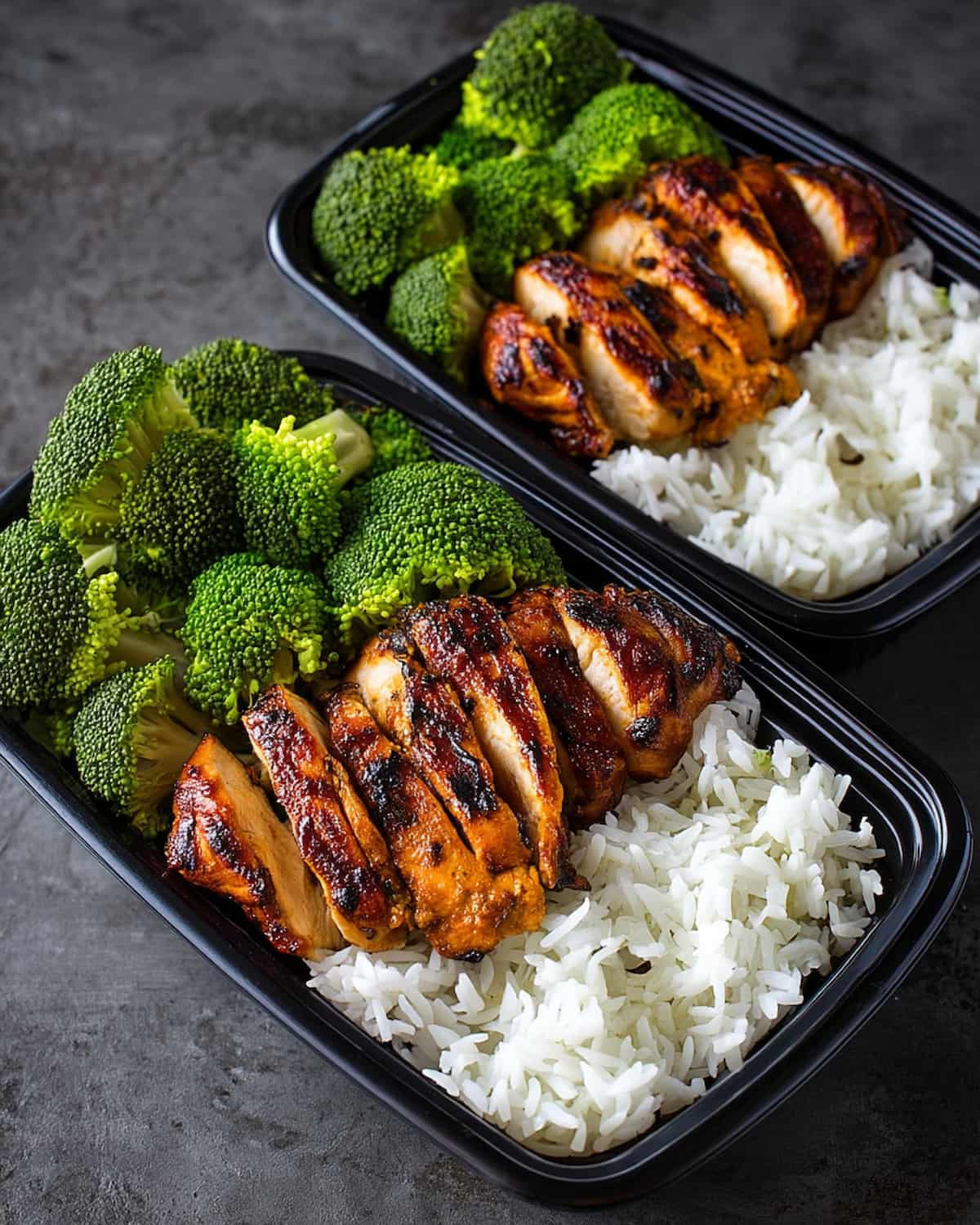 Chicken rice broccoli meal prep containers with glazed sliced chicken breast, fluffy white rice, and steamed broccoli florets.