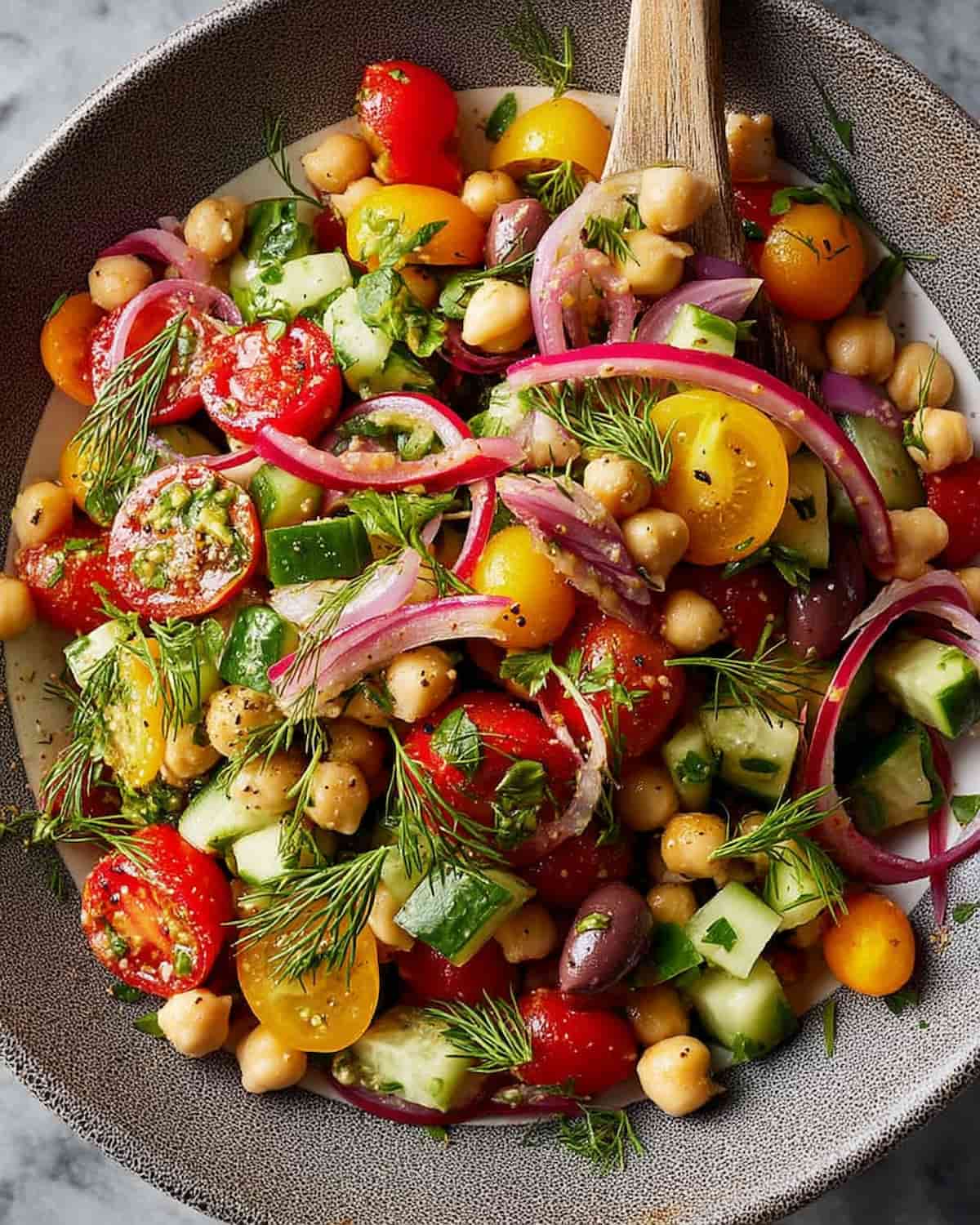 Chickpea salad meal prep with chickpeas, cherry tomatoes, cucumbers, red onion, olives.