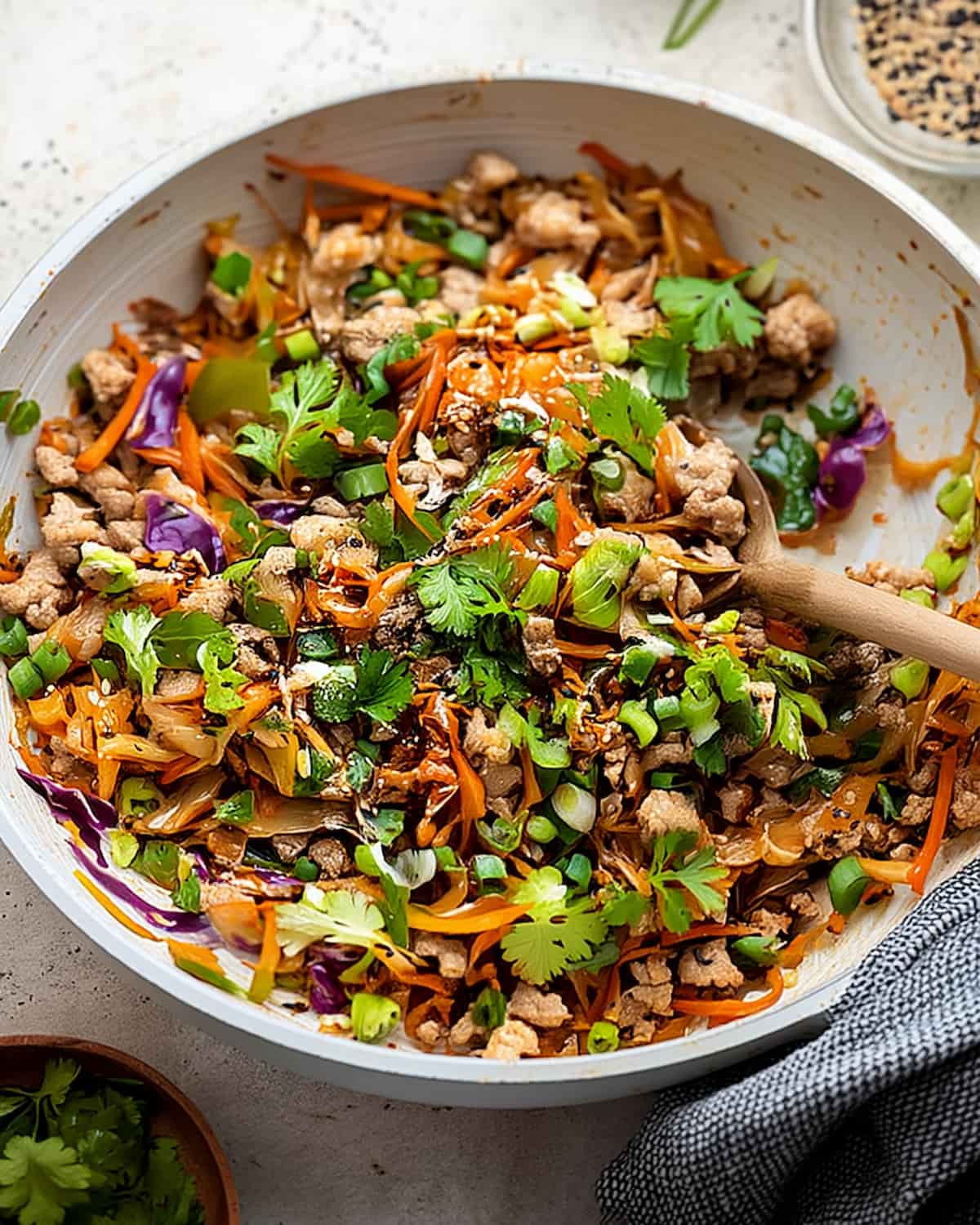 Egg roll in a bowl meal prep with ground pork, shredded cabbage, carrots, bell peppers.