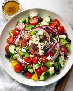 Greek salad meal prep with cucumbers, cherry tomatoes, red onion, Kalamata olives, feta cheese.