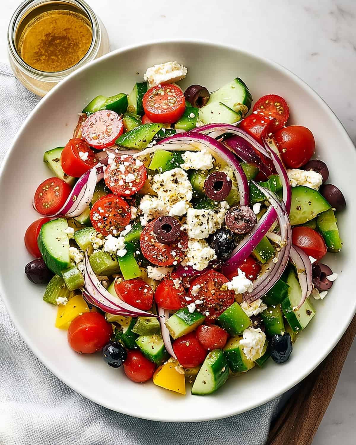 Greek salad meal prep with cucumbers, cherry tomatoes, red onion, Kalamata olives, feta cheese.
