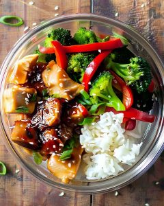 Teriyaki chicken meal prep bowl with glazed chicken, white rice, steamed broccoli, red bell peppers.