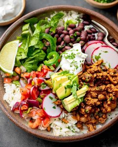 Bowl of ground turkey burrito bowl meal prep with seasoned turkey, rice, black beans, avocado, fresh veggies.