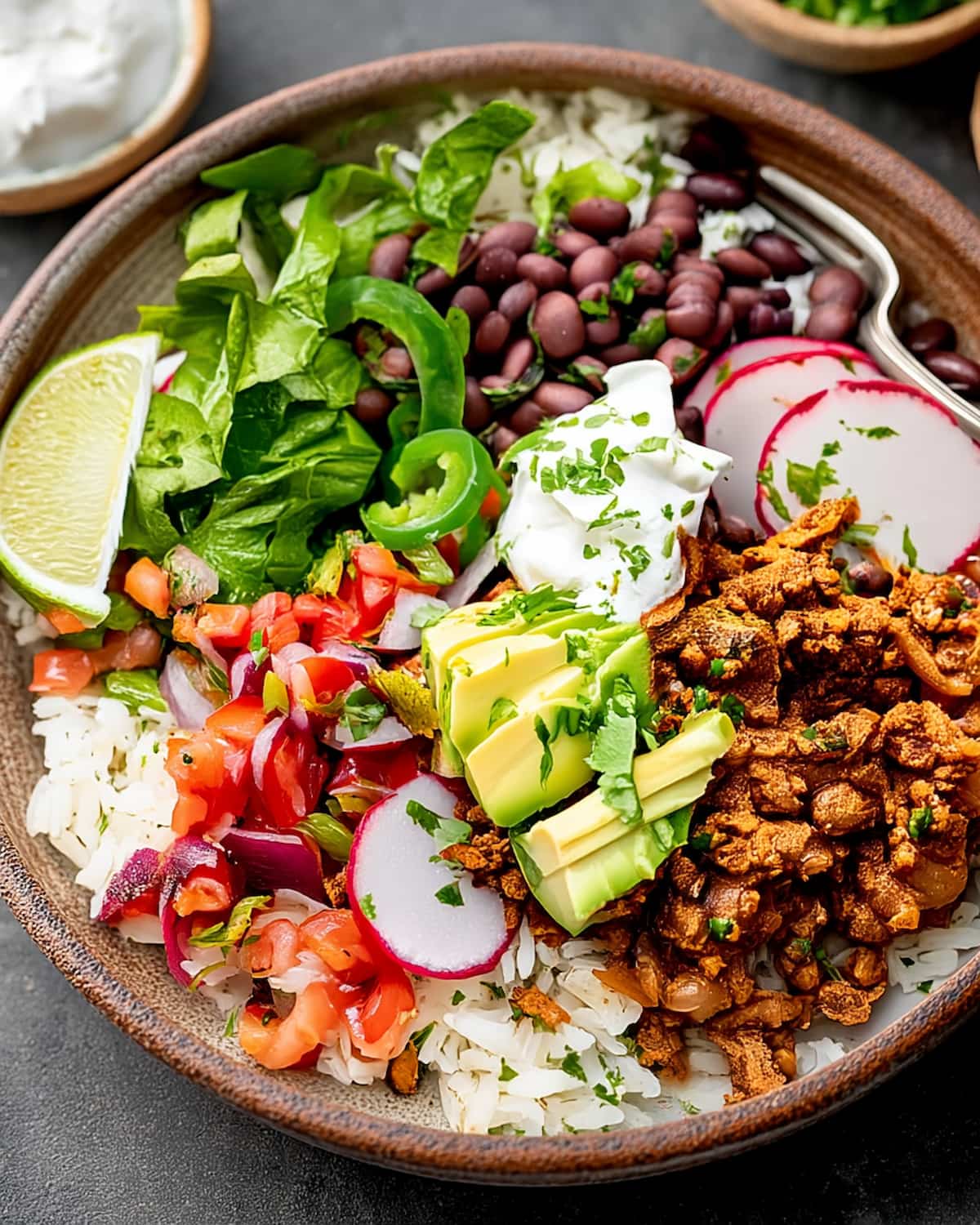 Bowl of ground turkey burrito bowl meal prep with seasoned turkey, rice, black beans, avocado, fresh veggies.
