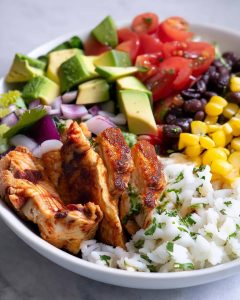 Low carb chicken burrito bowl with grilled chicken, cauliflower rice, avocado, tomatoes, black beans, corn.