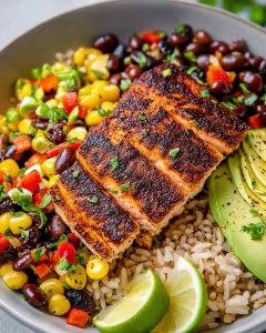 Southwest salmon bowl meal prep with blackened salmon, brown rice, black beans, corn, avocado slices.