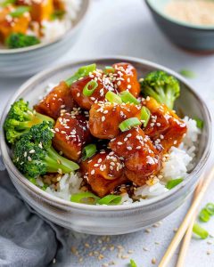 Teriyaki Tofu Meal Prep with glazed tofu, broccoli, and rice, topped with sesame seeds and green onions.