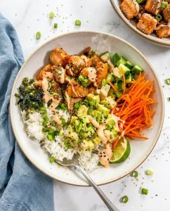Crunchy Salmon Bowl with sushi rice, crispy salmon bites, cucumbers, avocado, nori, and spicy mayo drizzle